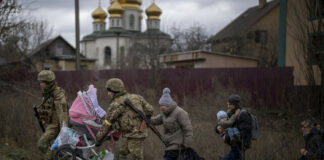 Солдаты помогают семье переправляться через реку Ирпень на окраине Киева