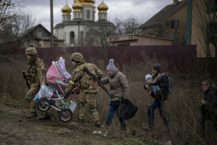 Солдаты помогают семье переправляться через реку Ирпень на окраине Киева